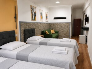 A hotel room with two beds, a green sofa, a stone accent wall, and a flat-screen TV. - Hotel Efesian B&B City Center - Harbour (Kuşadası)