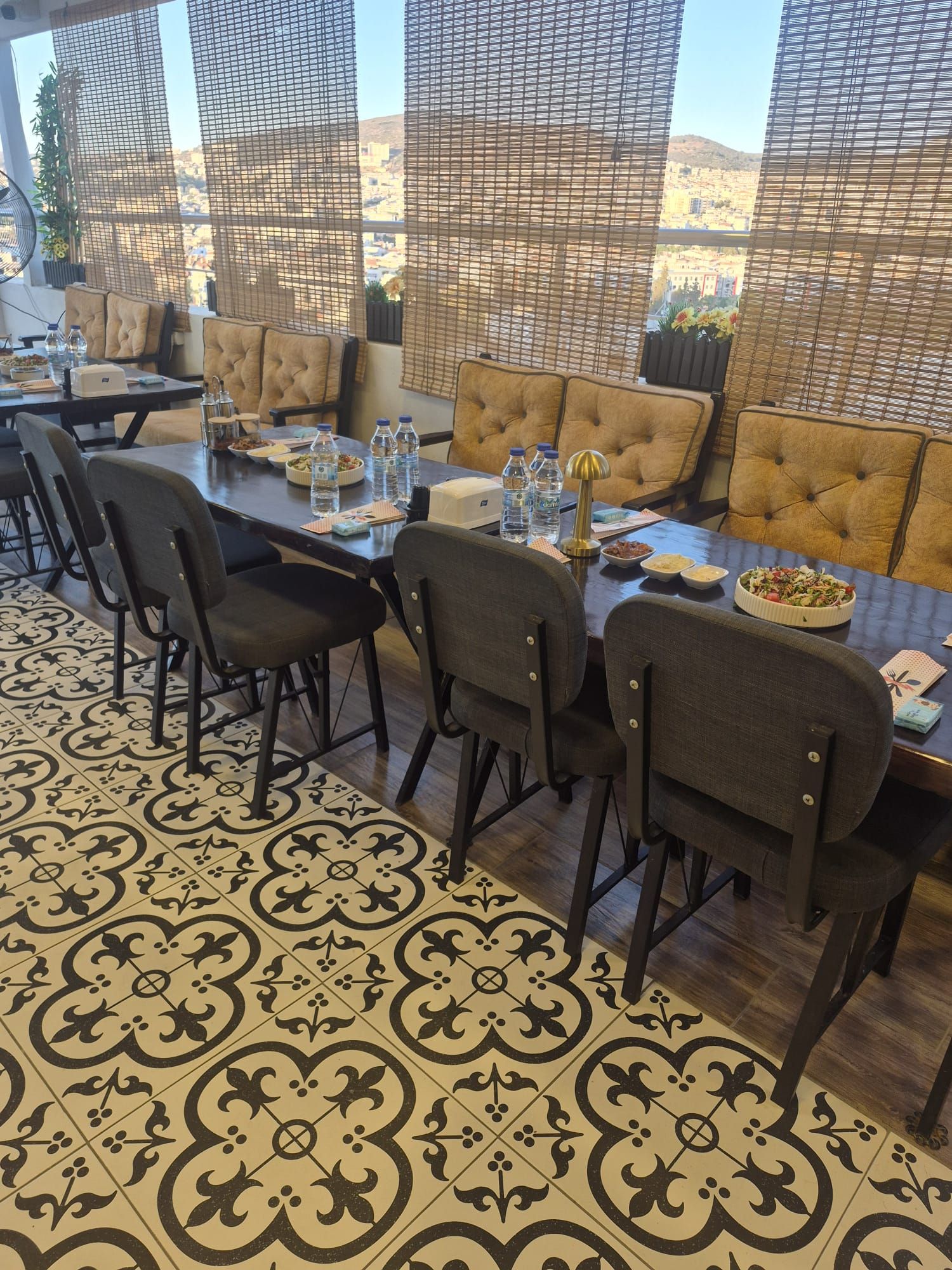 Una zona pranzo con un tavolo lungo, diverse sedie e un pavimento decorato.