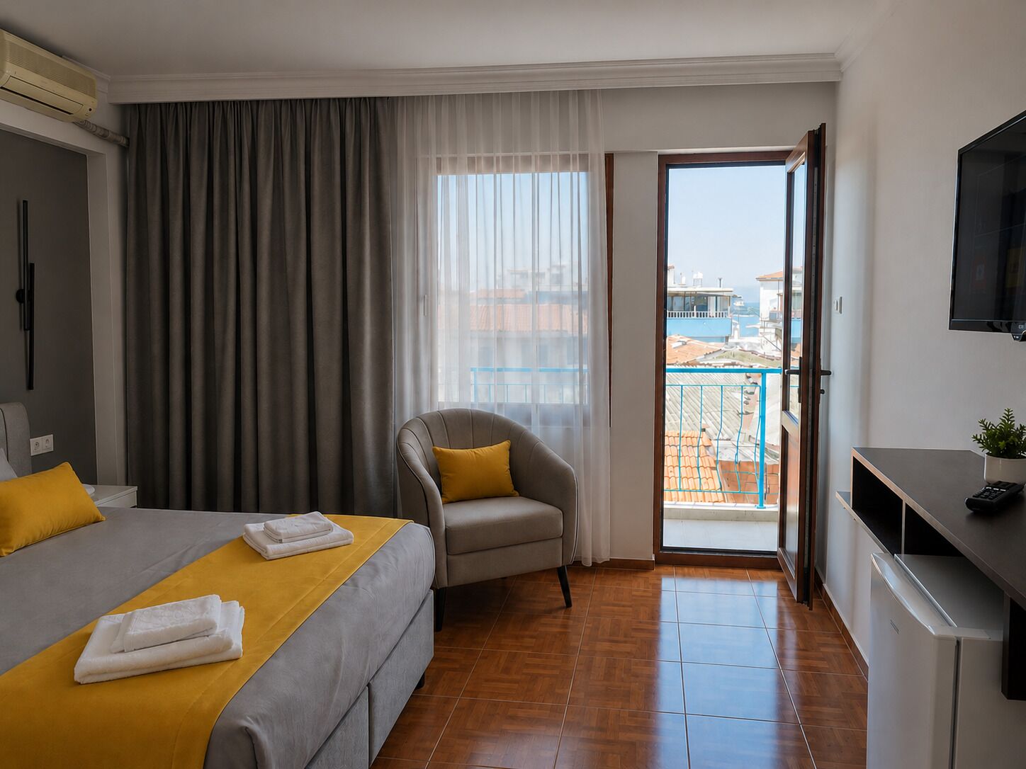 Een hotelkamer met een bed, een stoel, een bureau, een televisie en een balkon met uitzicht.