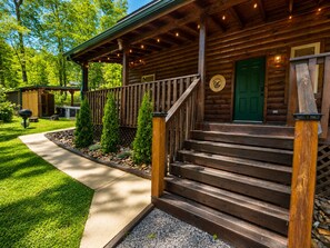 A wooden cabin with a porch, steps, and a green door. - Cozy Cabin near Pigeon Forge and Gatlinburg, Hot Tub, Fire Pit & Arcade (Sevierville)