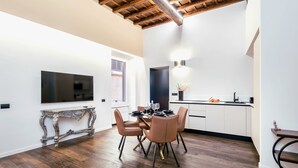 A modern kitchen with white cabinets, a dining table with chairs, and a TV mounted on the wall. - Pantheon- Finely renovated and furnished apartment 60 sqm 4 beds (Roma)