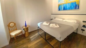A bedroom with a bed, a chair, a small round table, and a painting on the wall. - Pantheon- Finely renovated and furnished apartment 60 sqm 4 beds (Roma)