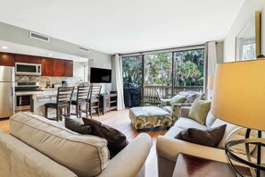 Una sala de estar moderna con sofá, reposapiés y un comedor con sillas y mesa.