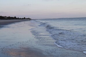 Ein Strand mit weitem Sandstreifen und sanften Wellen.