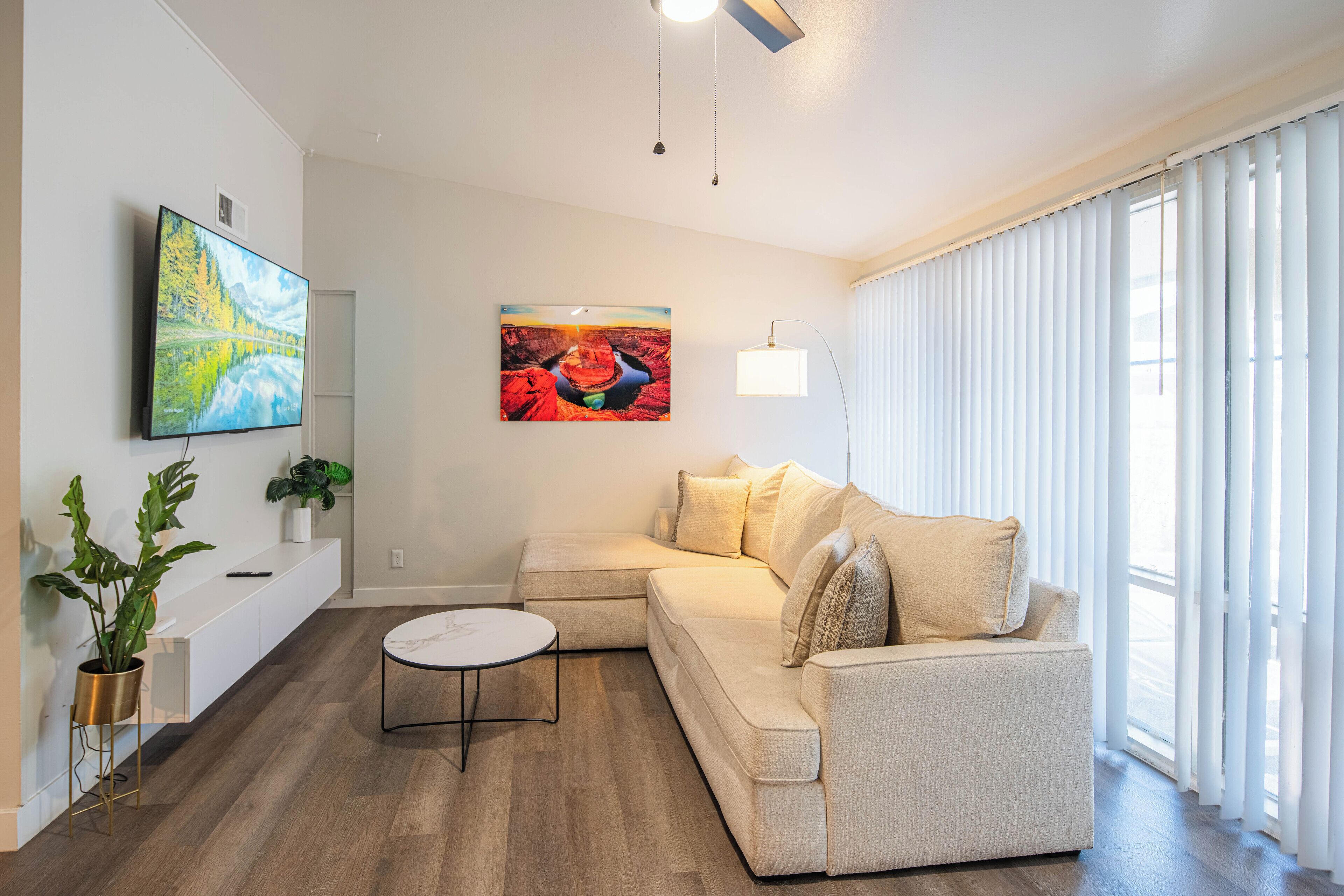 A modern living room with a beige sofa, a round coffee table, and a painting on the wall.