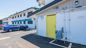 A building with a yellow door labeled "1723-4" and a blue car parked in front. - Dwell 1723-1 (Scottsdale)