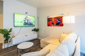 Ett modernt vardagsrum med en platt-TV, en soffa, ett soffbord och en lampa.
