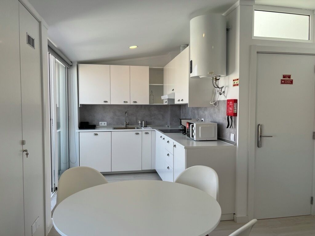 Une cuisine moderne avec des meubles blancs, une table de salle à manger ronde et un four à micro-ondes encastré.