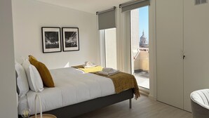 Ein modernes Schlafzimmer mit einem Bett, einem Nachttisch, einer Lampe und einem Fenster mit Blick auf die Stadt.