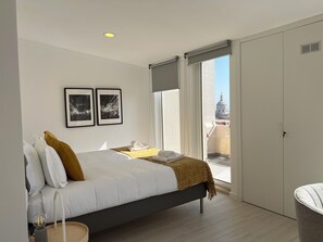 Ein modernes Schlafzimmer mit einem Bett, einem Nachttisch, einer Lampe und einem Fenster mit Blick auf die Stadt.