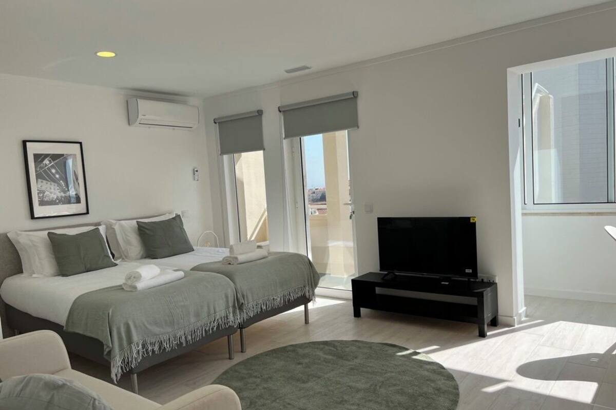 A modern bedroom with a bed, a TV, and a large window.