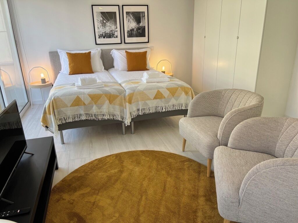 Une chambre d’hôtel avec deux lits, un canapé, une télévision et une grande fenêtre.