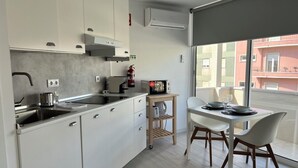 Eine moderne Küche mit weißen Schränken, einem eingebauten Herd und einem kleinen Essbereich mit Tisch und Stühlen.