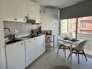 Eine moderne Küche mit weißen Schränken, einem eingebauten Herd und einem kleinen Essbereich mit Tisch und Stühlen.