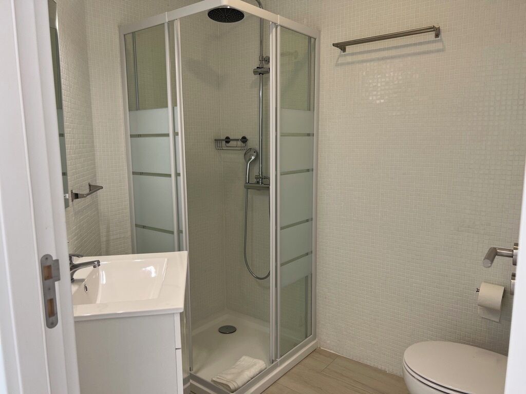 A modern bathroom with a glass-enclosed shower, a white sink, and a toilet.