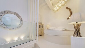 A modern bedroom with a curved bed, a round mirror, a bedside lamp, and a decorative wooden piece. - Piazza Navona Hydromassage Tub 7 people (Rome)