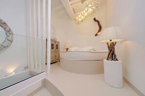 A modern bedroom with a glass railing, a round bed, a wooden cabinet, and a unique wall light fixture. - Piazza Navona Hydromassage Tub 7 people (Rome)