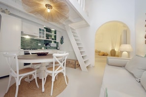 A modern kitchen with white cabinetry, a dining table with chairs, a staircase, and a living area with a sofa and lamp. - Piazza Navona Hydromassage Tub 7 people (Rome)