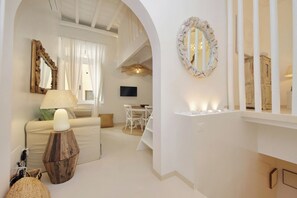 Ein modernes Wohnzimmer mit Sofa, einer Lampe, einem Spiegel und einem Essbereich mit Tisch und Stühlen.