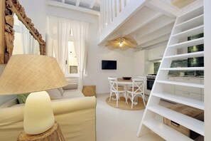 A modern interior with a sofa, dining table, chairs, a TV, and a kitchen area. - Piazza Navona Hydromassage Tub 7 people (Rome)