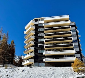 A multi-story building with balconies, surrounded by trees and snow. - 5th floor, view resort/mountain, balcony, tv, 23m², Vars (Vars)