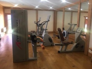 Ein Fitnessraum mit Cardiogeräten und Krafttrainingsgeräten, Holzböden und großen Spiegeln an den Wänden.