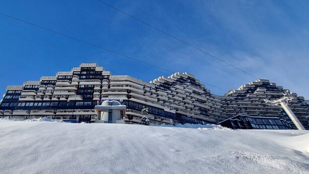 Ein modernes Gebäude mit einem einzigartigen architektonischen Design, das mehrere Ebenen und eine markante zentrale Struktur aufweist.