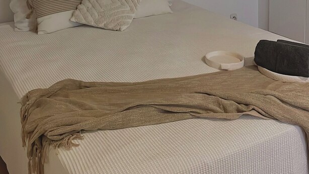 Un dormitorio con cama, almohadas, mesita de noche y armario.