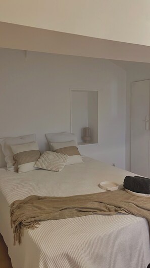 Une chambre à coucher avec un lit, des oreillers, une table de chevet et une armoire.