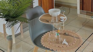 Una cocina moderna con comedor, que presenta una mesa redonda con mantel individual, sillas, un reloj en la pared y una planta en maceta.