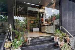 A hotel entrance with a glass door, indoor plants, and a staircase leading to the lobby. - Classic Townhouse Aroma Residency (Jaipur)