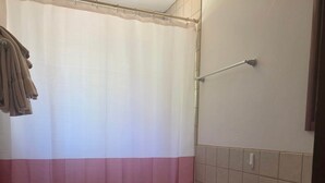 Et badeværelse med toilet, vask og bruseforhæng.