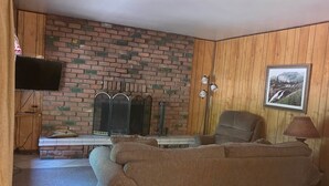 En stue med murstensvæg, sofa, fjernsyn og et indrammet billede.