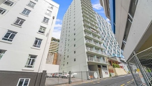 A multi-story building with balconies, a gated entrance, and a clear sky. - Comfortable Studio, Aircon, Central Location (Auckland CBD)