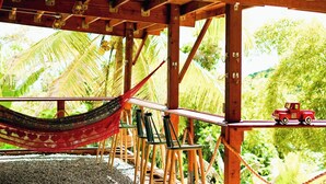 Una estructura de madera con una hamaca, sillas y un coche de juguete en una plataforma.