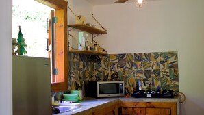 Una cocina con ventilador de techo de madera, microondas y un armario de madera.