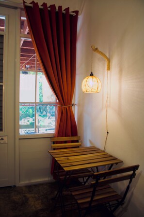 A room with a wooden table and bench, a window with a view of greenery, and a hanging lamp. - Private Finca Ki' •3BR • Hammock Terrace • El Yunque • Ceiba Ferry • Easy-Access (NAGUABO)