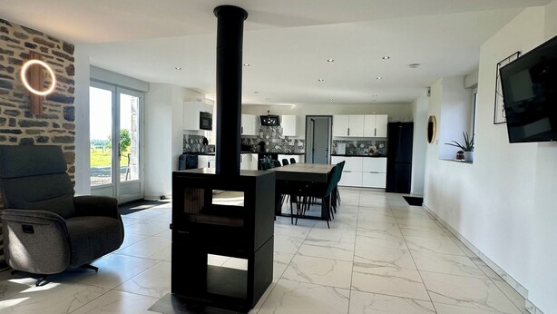 A modern living room with a fireplace, a dining area, and a kitchen in the background.