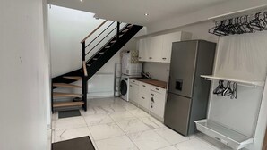 A modern kitchen with white cabinets, a stainless steel refrigerator, and a built-in washing machine.