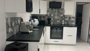 A modern kitchen with white cabinets, a black countertop, and patterned backsplash tiles.
