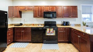 A kitchen with wooden cabinets, a black refrigerator, a microwave, a stove, and a dishwasher. - Boston Getaway, Close to Airport (Boston)
