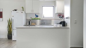 Una cucina moderna con mobili bianchi, un lavello in acciaio inossidabile e una finestra sopra il piano di lavoro.