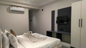 A modern hotel room with a bed, a flat-screen TV, a wardrobe, and an air conditioning unit. - Heaven X Inn Hotel (Indore)