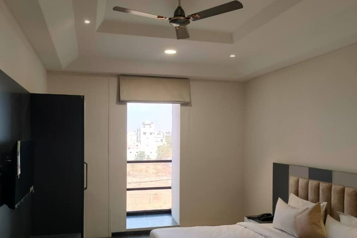 Ein Hotelzimmer mit Bett, Deckenventilator, Fernseher und Blick ins Freie.