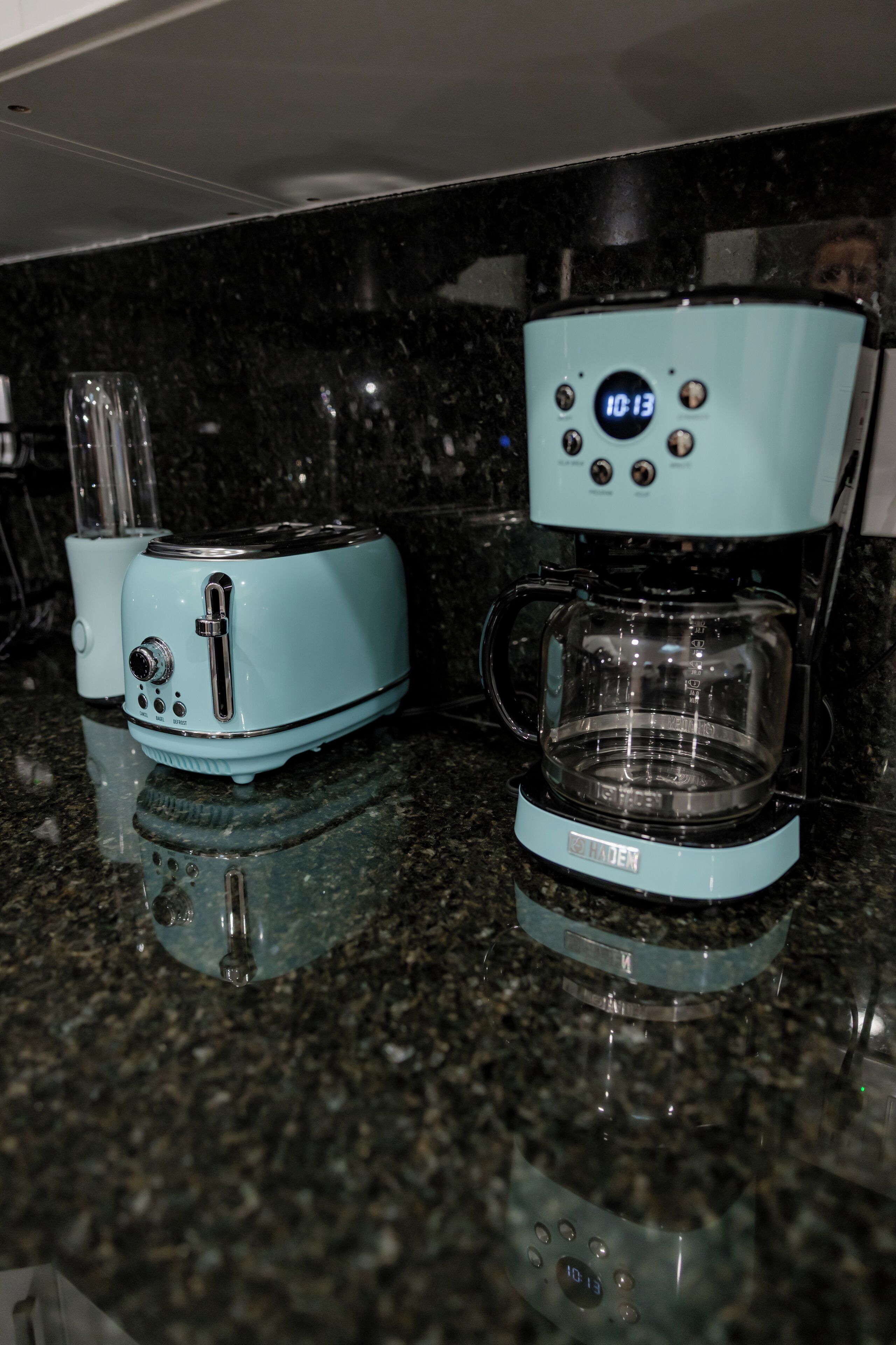 Una cocina con cafetera y tostadora sobre una encimera de granito.