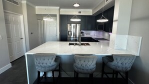 A modern kitchen with a large island, dark cabinetry, and pendant lighting. - Water View with Balcony- newly renovated Contemporary style (Lantana)