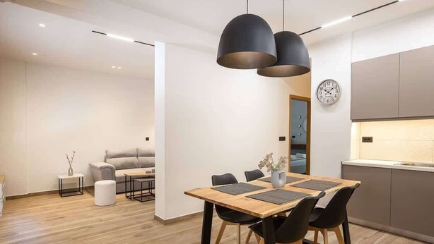 Una cucina moderna con un tavolo da pranzo in legno, sedie nere e lampade a sospensione.