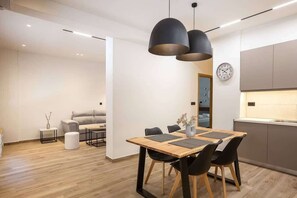 Een moderne keuken met een houten eettafel, zwarte stoelen en hanglampen.