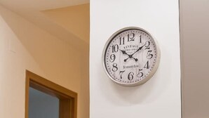 Orologio da parete dal design vintage, una porta che dà su un'altra stanza e un vaso con fiori su un tavolo.