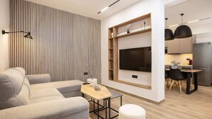 Un soggiorno moderno con un divano, un tavolino in legno e una TV a parete.